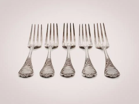 Five silver forks arranged in a row on white background Stock Photos