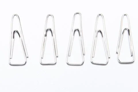 Five Silver Paper Clips in a Row on White Background, Office Supplies, Mini.. Foto stock
