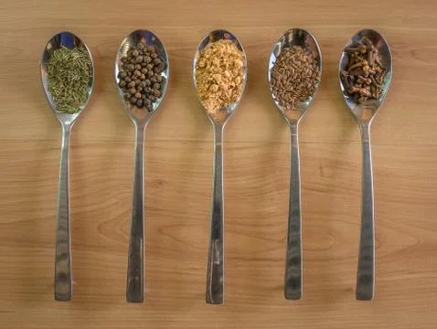 Five silver spoons with various spices Stock Photos