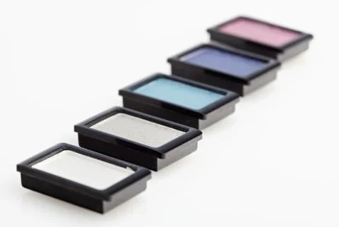 Five small multicolored eye-shadows arranged in line on white Foto stock