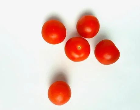 Five small ripe red tomatoes on a white background. Stock Photos