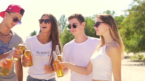 Five smiling friends clinks bottles with beer at beach Stock Footage 67349133