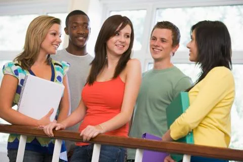 Five students in corridor leaning on railing with notebooks Stock Photos
