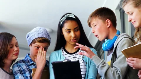 Five students learning around tablet in school headphone boy tapping screen Stockbeeldmateriaal 332981868