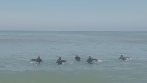 Five surfers paddling facing ocean wide shot 動画素材 345216336