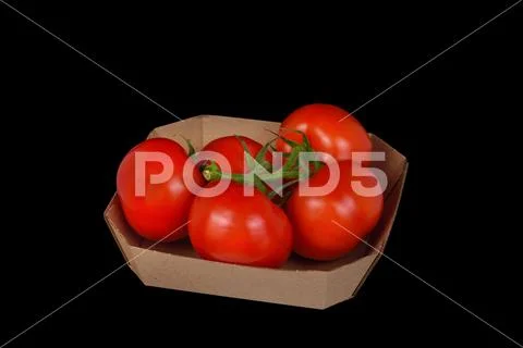 Five tomatoes in a cardboard box on a black background. ~ Hi Res #152501243