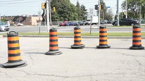 Five traffic delineators drums barrels pylons cylinders in parking lot with road Stock Footage 252042533
