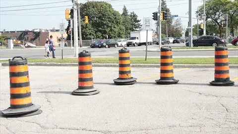 Five traffic delineators drums barrels pylons cylinders in parking lot with road Stock Footage 252042605