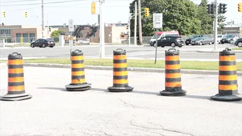 Five traffic delineators drums barrels pylons cylinders in parking lot with road Stock Footage 252042636