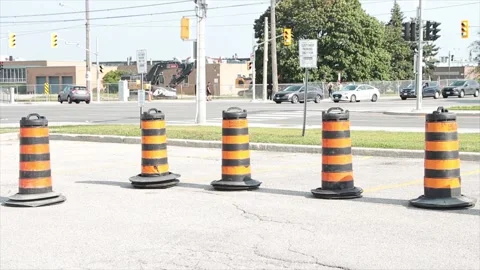 Five traffic delineators drums barrels pylons cylinders in parking lot with road Stock Footage 252042681