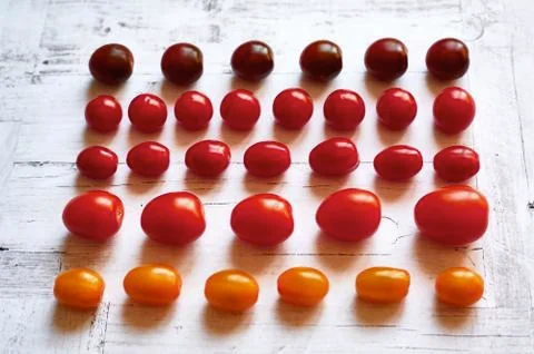 Five types of cherry tomatoes on a light wooden background from above close u Stock Photos