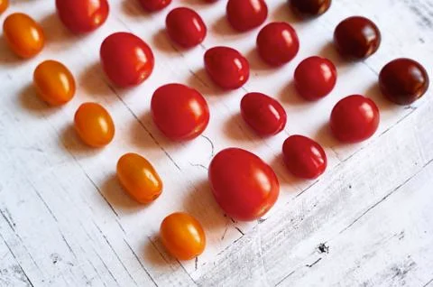 Five types of cherry tomatoes on a light wooden background from above close up Stock Photos