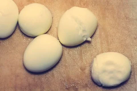 Five white boiled eggs for ingredients lie on a cutting board in the kitchen. Stock Photos