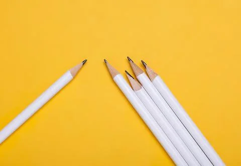 Five white pencils with sharp tips on yellow background Stock Photos