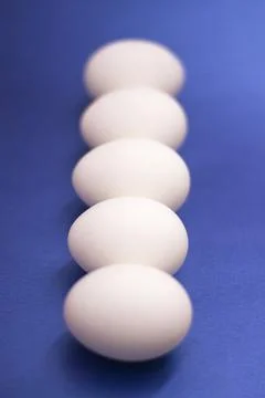 Five white raw eggs lie on the table. Vertical photo, large eggs. Preparing f Stock Photos
