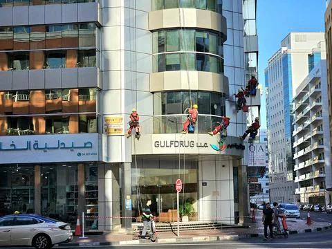 Five window cleaners rappel down a modern high-rise in Dubai, UAE, Stock Photos