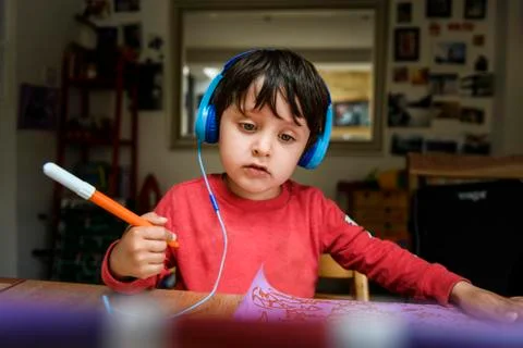 A five year old boy in blue headphones having an interactive learning session, Stock Photos