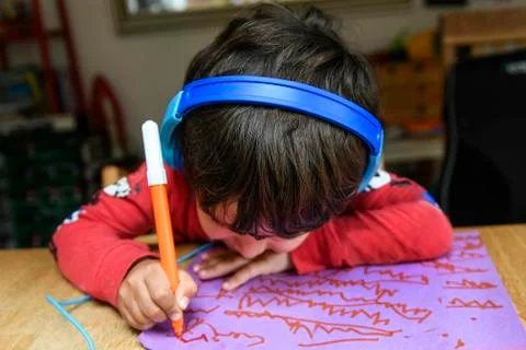 A five year old boy in blue headphones having an interactive learning session, Stock Photos