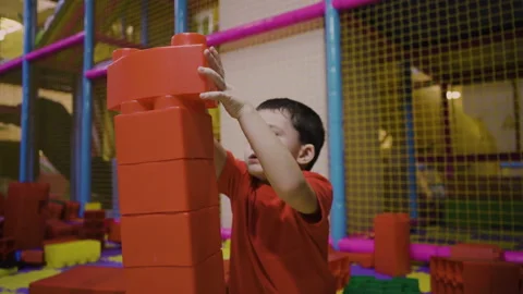 A five-year-old boy builds a tower from a large construction set Stock Footage 169395567