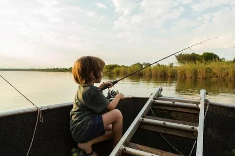 A five year old boy fishing from a boat on the Zambezi River, Botswana Stock Photos
