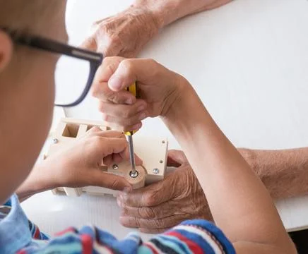 A five-year-old boy independently assembles a wooden construction kit with .. Stock-Fotos