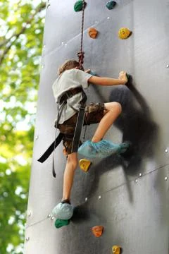 Five year old boy learning to climb the rock wall outside Stock Photos