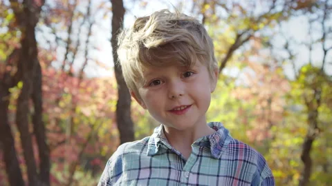 Five year old boy looks into camera cheerfully in autumn forest slow motion Video stock 194460870