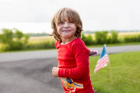 A five year old boy in a red shirt riding his bike on a quiet residential Stock Photos