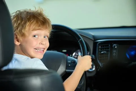 Five-year-old boy sits behind the wheel and pretends to drive a car Stock Photos