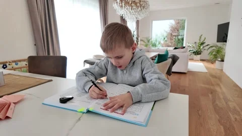 Five year old boy sitting with a book solving math exercises. Concept of early Stock Footage 329567319