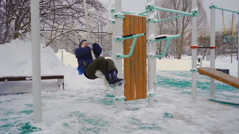 A five-year-old boy swings in the winter on a hanging rope on the playground Stock Footage 169527655