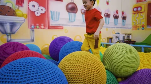 A five-year-old boy in a tracksuit jumps on inflatable knitted balls Stock Footage 169395831