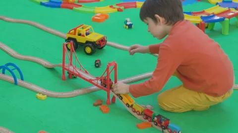 Five years old boy playing with wooden railway on the floor in the children's Stock Footage 98455385