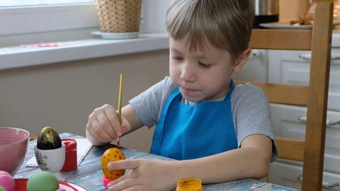 Five years old child boy kid coloring easter eggs in the kitchen. Stock Footage 122803036