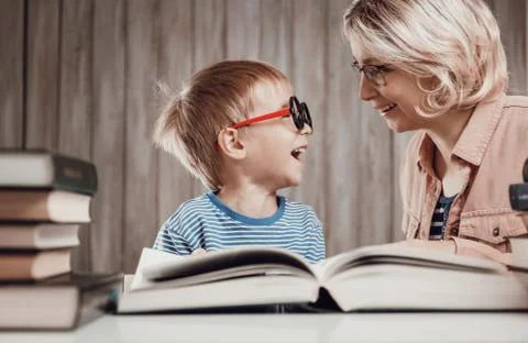 Five years old child reading a book at home with mother Stock Photos