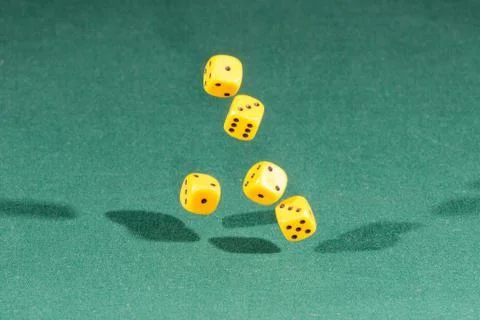 Five yellow dices falling on a green table Stock Photos