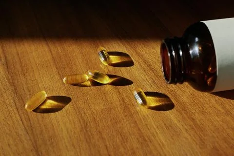 Five yellow translucent dietary supplement pills in sunshine Stock Photos