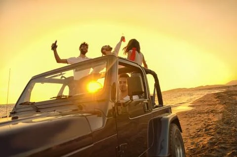 Five young people having fun in convertible car at the beach at sunset. 写真素材