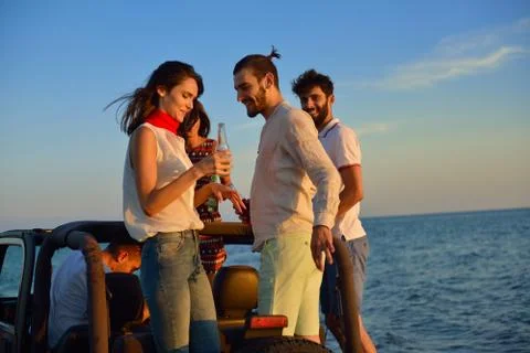 Five young people having fun in convertible car at the beach at sunset. Stock-Fotos