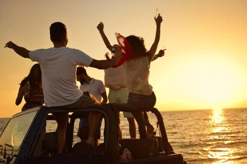 Five young people having fun in convertible car at the beach at sunset. Foto stock