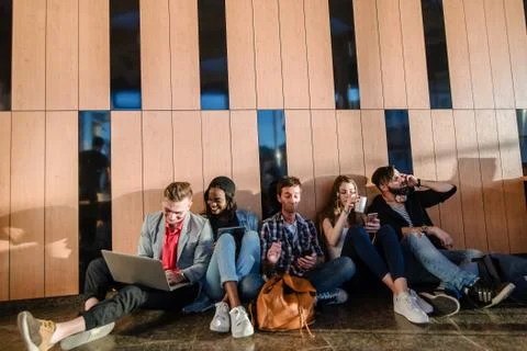 Five young people sitting on the floor in the commin room and relaxing. Stock Photos