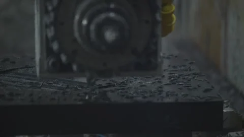 A fixed camera shows a computer controlled milling machine cutting a black Stock Footage 348799390