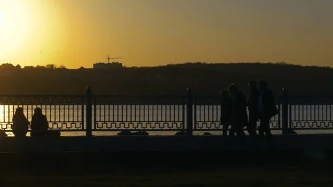 Fixed look of sunset at like and passers-by walking at quay Video stock 74753429