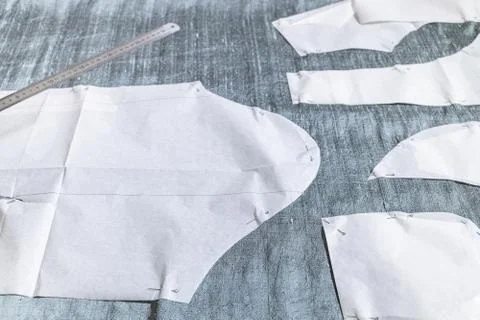 Fixed paper sewing pattern layouts on gray fabric Stock Photos