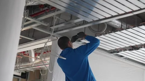 Fixing ceiling grid system with power drill in interior fit out, worker Stock Footage 332584275