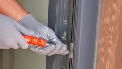 Fixing a door lock with a screwdriver in a residential setting Stock Footage 345621897