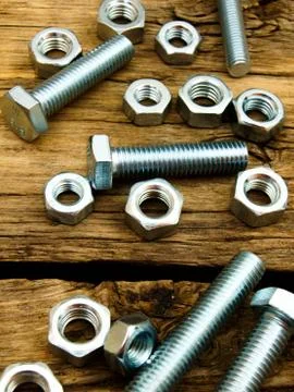 Fixing elements (nuts, screws) on wooden background. Fotos Stock