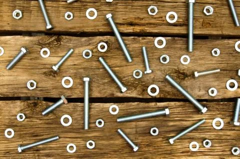 Fixing elements (nuts, washers, screws) on wooden background. Fotos Stock