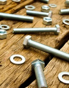 Fixing elements (nuts, washers, screws) on wooden background. Fotos Stock