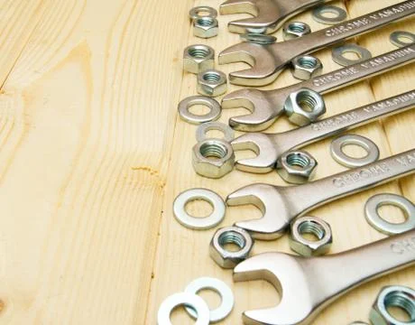Fixing elements (nuts, washers, screws) and wrenches on wooden background. Foto stock